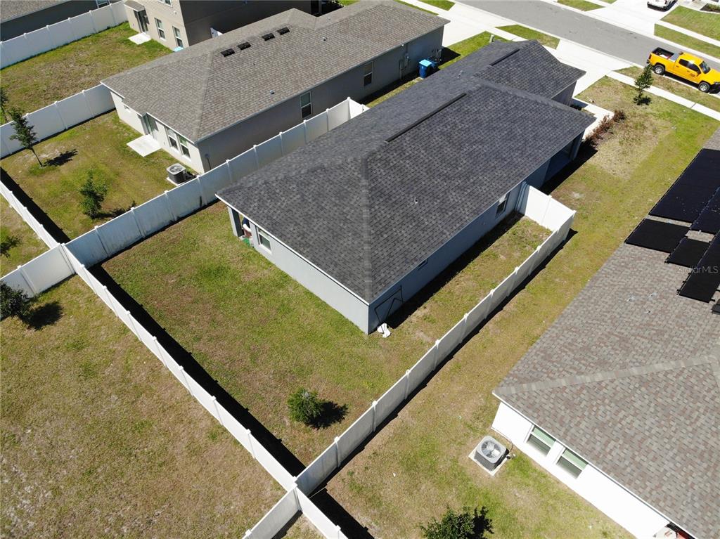 An aerial view shows a single-story house with a fenced backyard and gray roof — 1923 GOLDEN BEAK DRIVE, EAGLE LAKE, FL
