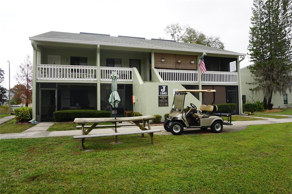 A two-story apartment building with a golf cart parked in front on the lawn — 1865 MAZO MANOR UNIT J5, LUTZ, FL