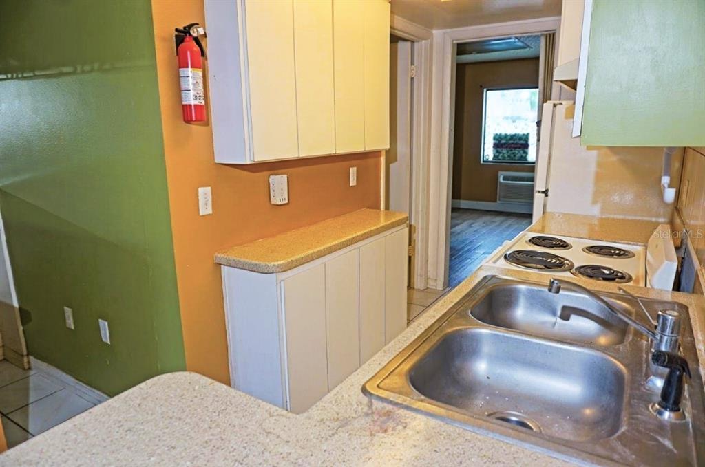 A kitchen features a double-basin sink, a stovetop, white cabinets, and a fire extinguisher — 1865 MAZO MANOR UNIT J5, LUTZ, FL