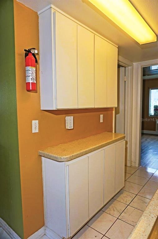 A kitchen area features white cabinets, a tan countertop, and a wall-mounted fire extinguisher — 1865 MAZO MANOR UNIT J5, LUTZ, FL