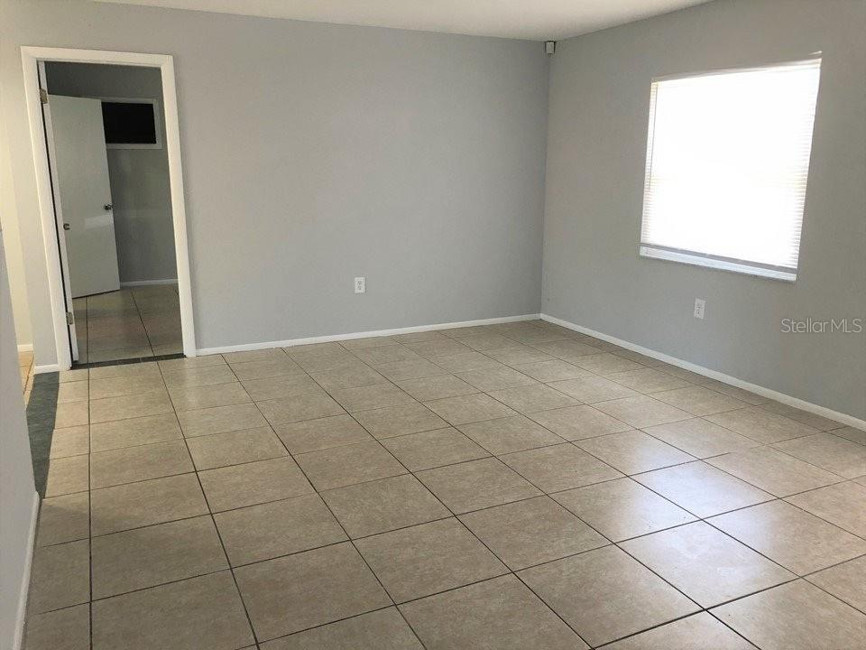 An empty room features light gray walls, large beige floor tiles, and a single window — 700 TRAILWOOD DRIVE, ALTAMONTE SPRINGS, FL