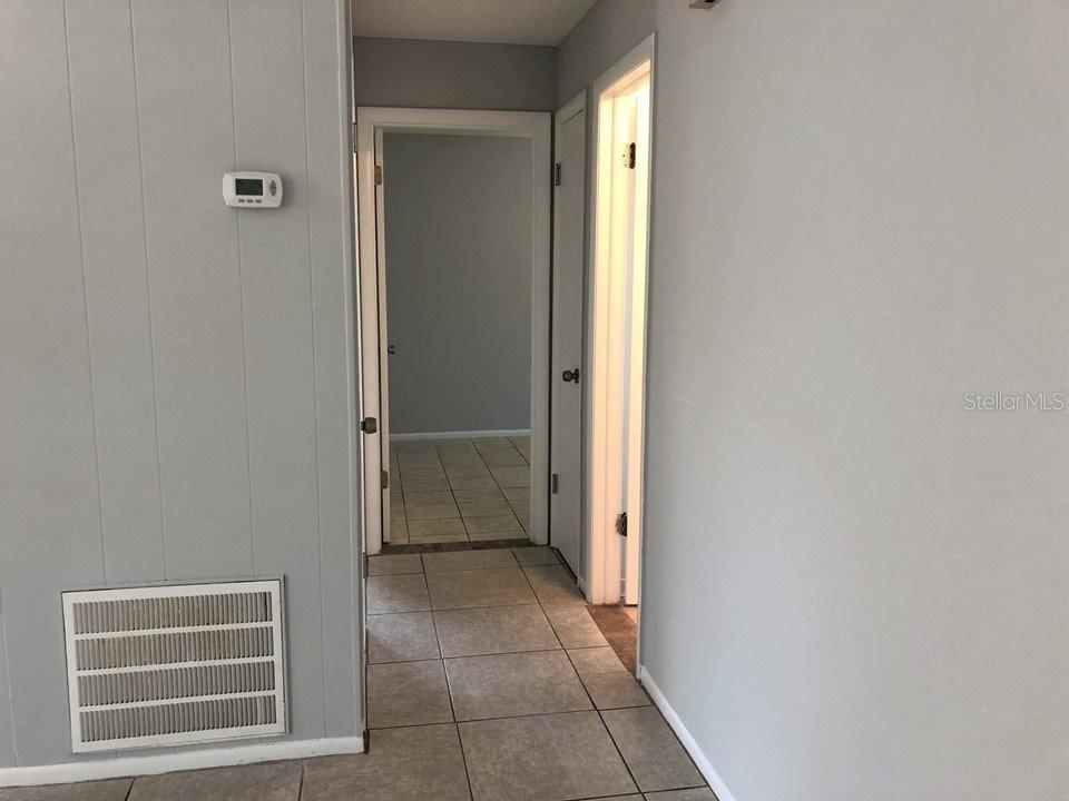 A hallway with light gray walls, tile flooring, and two open doorways — 700 TRAILWOOD DRIVE, ALTAMONTE SPRINGS, FL