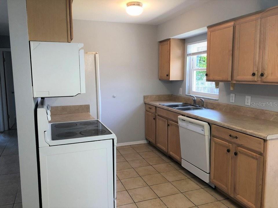 A kitchen features light wood cabinets, white appliances, beige countertops, and tan tile flooring — 700 TRAILWOOD DRIVE, ALTAMONTE SPRINGS, FL