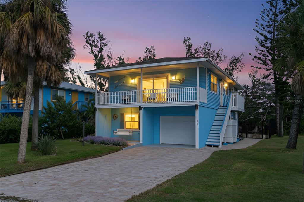 A two-story blue house with a white balcony, garage, and three palm trees in front — 2915 AVENUE C, HOLMES BEACH, FL