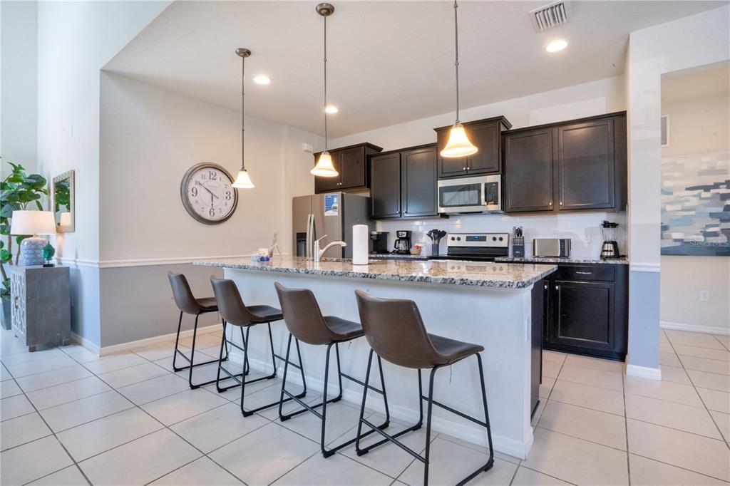 A living room features tile floors, a brown sectional, two gray chairs, and sliding doors — 8936 PRAGUE WAY, KISSIMMEE, FL