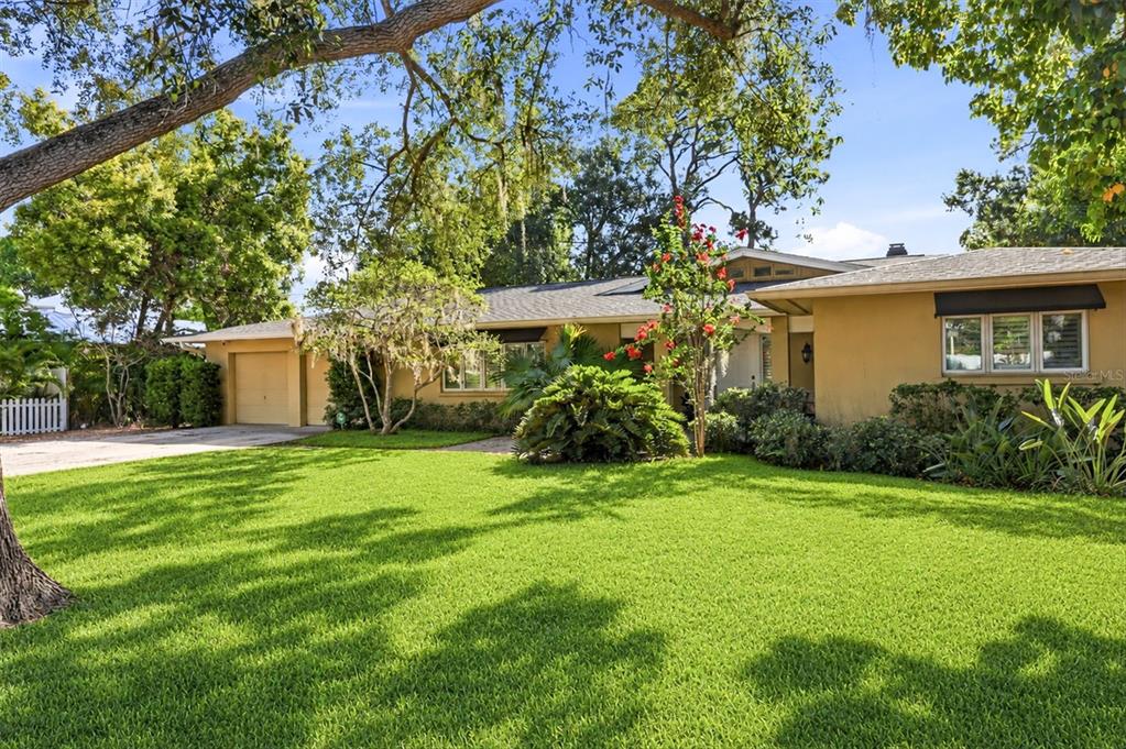 A single-story house with a tan exterior, a green lawn, and mature trees — 1041 CITRUS AVENUE, SARASOTA, FL