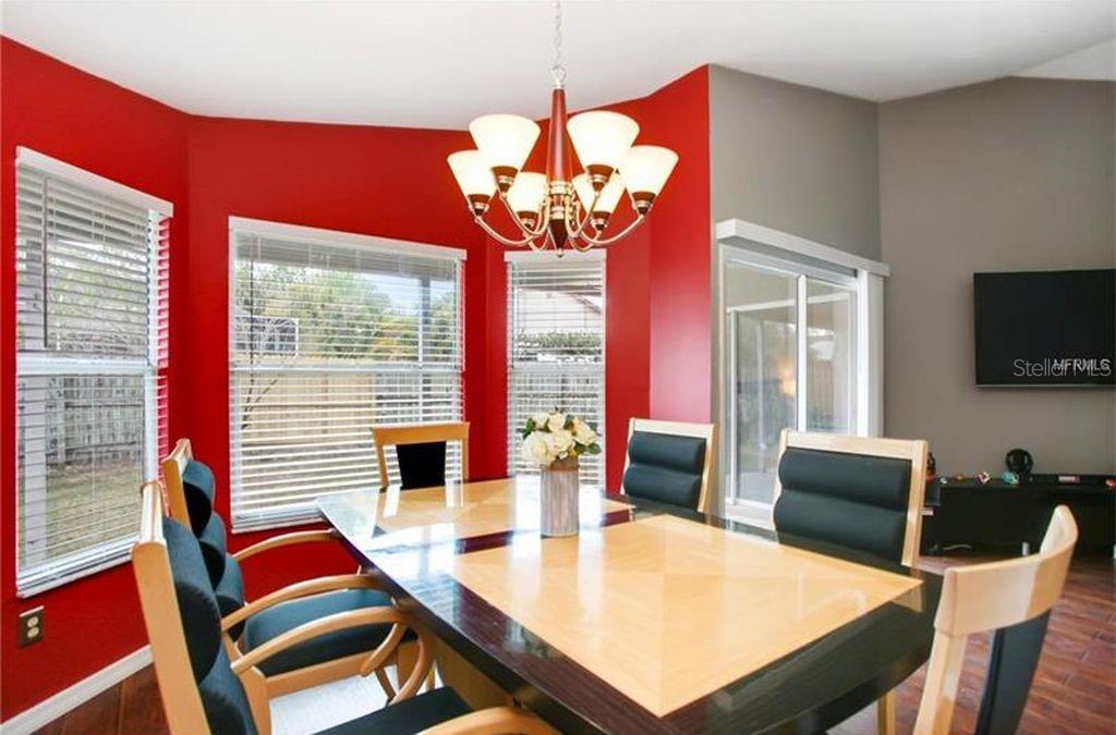 A dining room features a wooden table, six chairs, a chandelier, and red walls — 2003 GOLDENDALE COURT, BRANDON, FL
