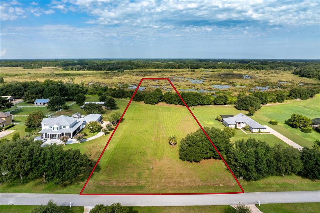 An aerial view shows a vacant, trapezoidal lot outlined in red bordering a marshy area — EAGLE RUN Lot #15, GROVELAND, FL