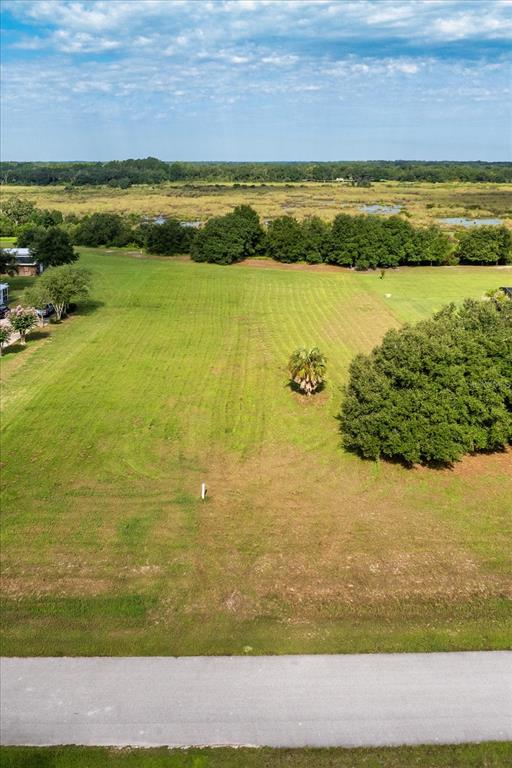 An aerial view shows a vacant grassy lot bordered by a road and distant trees — EAGLE RUN Lot #15, GROVELAND, FL