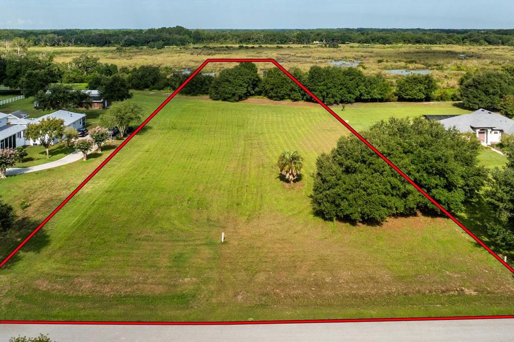An aerial view shows a vacant, grassy residential lot outlined in red — EAGLE RUN Lot #15, GROVELAND, FL