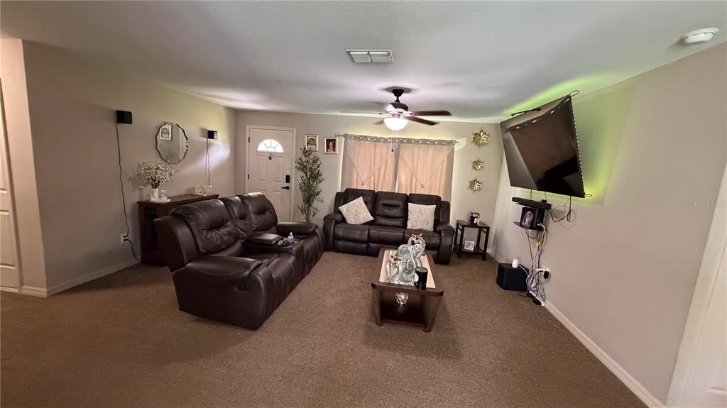 A living room features two brown leather sofas, a coffee table, and a wall-mounted television — 16222 SW 28TH COURT, OCALA, FL