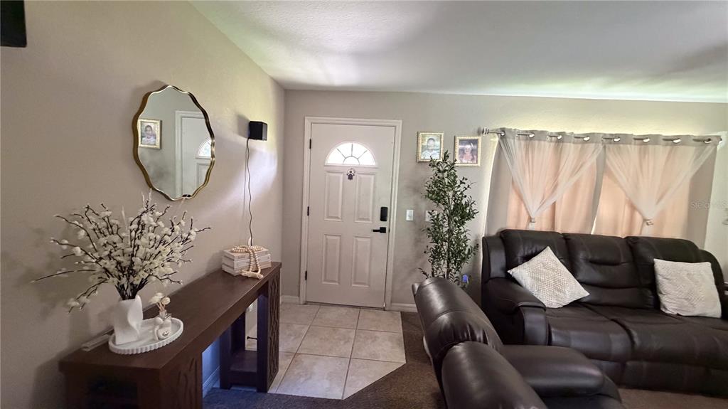 A living room features a front door, a console table, and a dark leather sofa — 16222 SW 28TH COURT, OCALA, FL