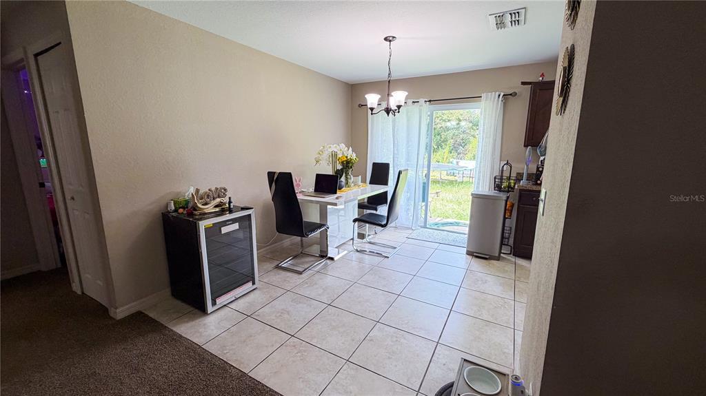 A dining area features tile flooring, a glass-topped table, and a sliding glass door — 16222 SW 28TH COURT, OCALA, FL