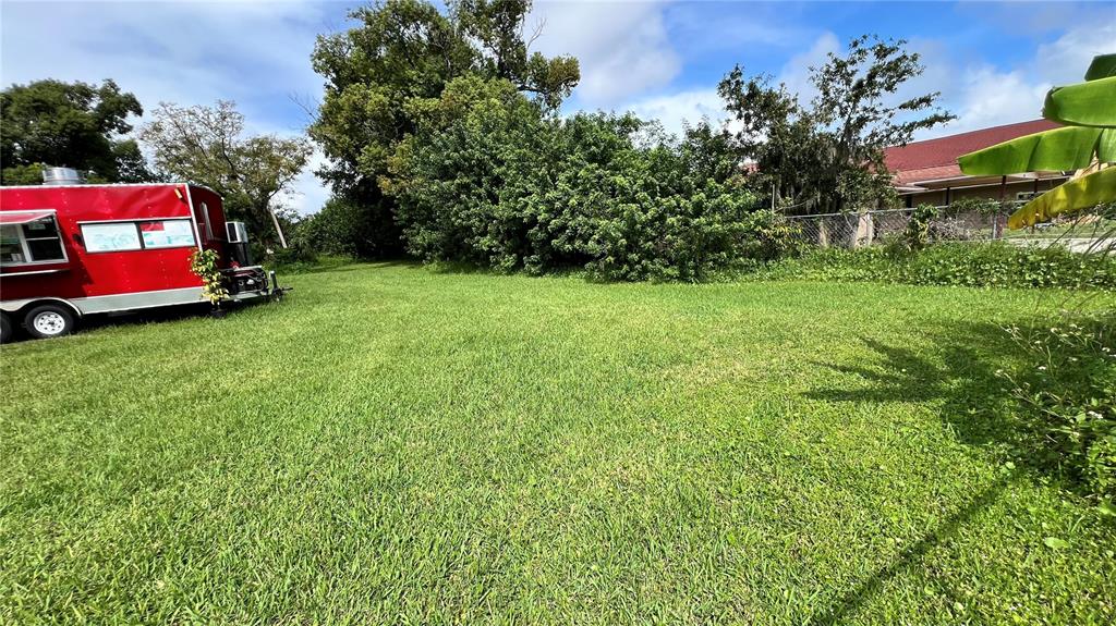 A red food truck sits on a grassy lot next to trees and a building — 730 N COMBEE ROAD, LAKELAND, FL
