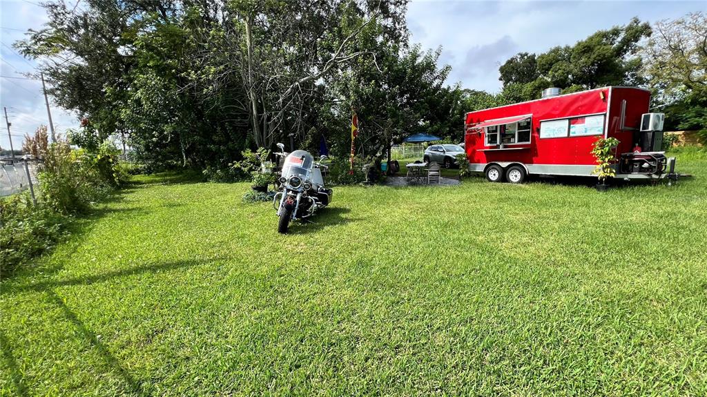 A red food trailer is parked on a grassy lot next to a motorcycle — 730 N COMBEE ROAD, LAKELAND, FL