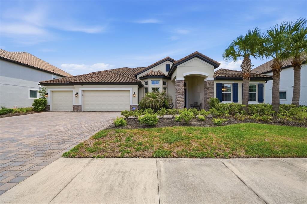 A single-story house with a three-car garage, stone accents, and a paved driveway — 7224 GRAYBROOK DRIVE, WESLEY CHAPEL, FL