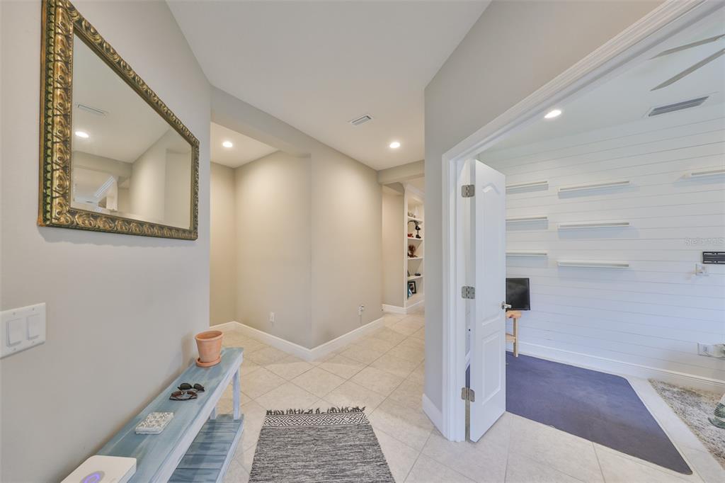 A hallway with a mirror and console table leads to a room with white shiplap walls — 11008 SAND PINE LANE, PARRISH, FL
