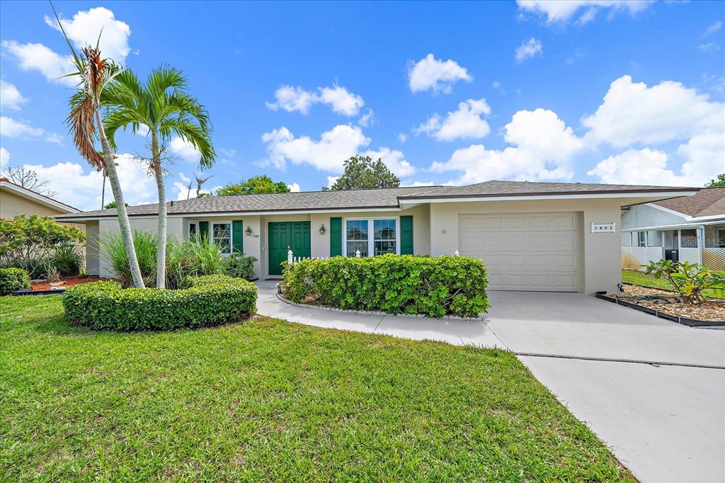 A single-story house with a green front door, a garage, and a landscaped front yard — 7403 14TH AVENUE W, BRADENTON, FL