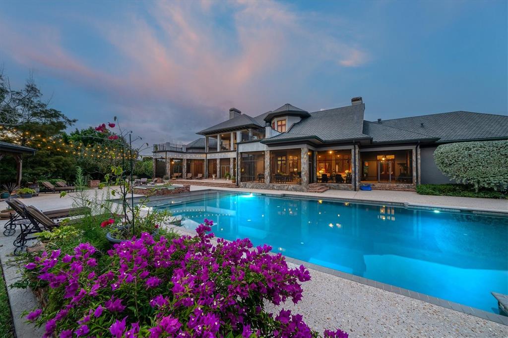 A large house with a swimming pool and purple flowers in the foreground at dusk — 586 WETHERSFIELD PLACE, MELBOURNE, FL