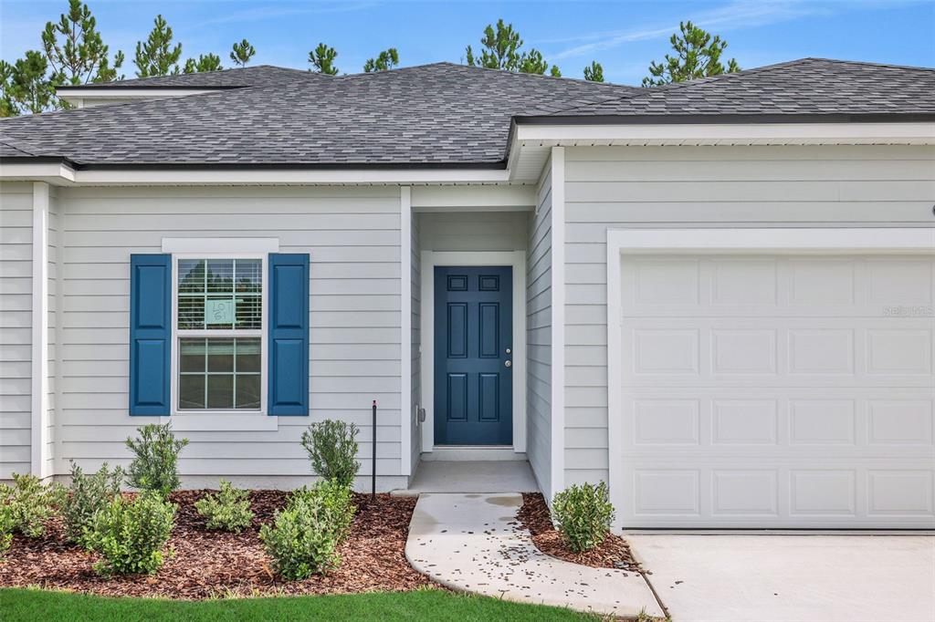 A single-story house exterior features light gray siding, a blue front door, and a garage — 2764 LAUREL FALLS DRIVE, GREEN COVE SPRINGS, FL