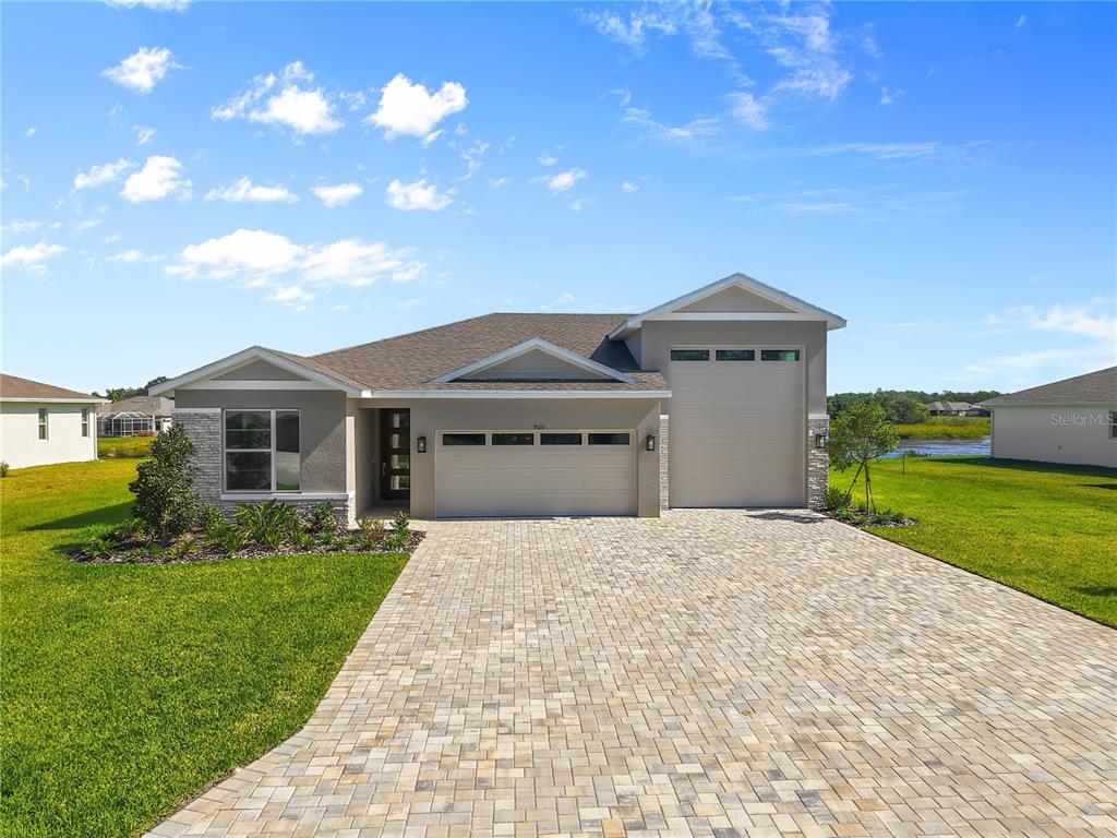 A single-story house with a paved driveway, two garage doors, and a stone-accented exterior — 9120 PLAYERS DRIVE, WEEKI WACHEE, FL