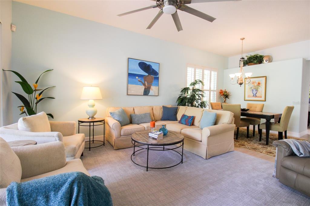A living room with a sectional sofa, armchairs, a coffee table, and an adjacent dining area — 6662 OAKBROOKE CIRCLE, BRADENTON, FL