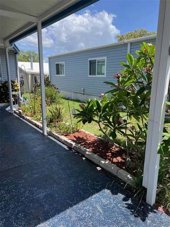 A view from a covered patio looking out at a garden bed and neighboring homes — 55 PALM FOREST DRIVE, LARGO, FL