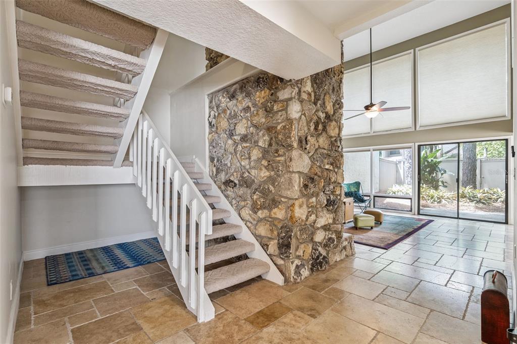 A foyer with a stone accent wall, carpeted staircase, and tile flooring leads to a living area — 117 RED CEDAR DRIVE, LONGWOOD, FL