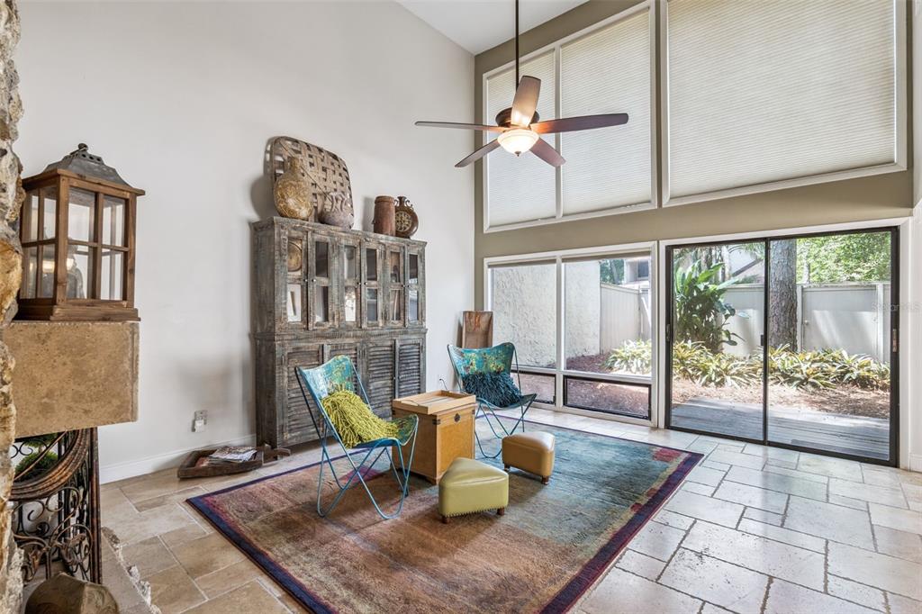 A sunlit living area features a tall cabinet, two butterfly chairs, and large floor-to-ceiling windows — 117 RED CEDAR DRIVE, LONGWOOD, FL