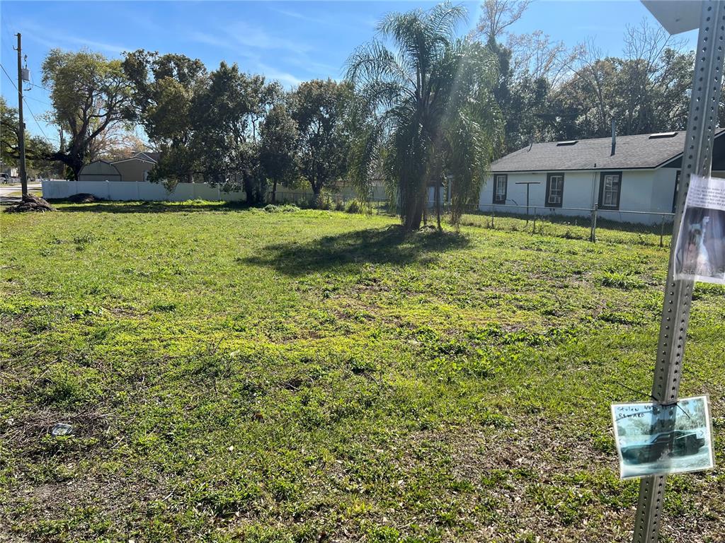 A vacant grassy lot features a palm tree and a neighboring house with a white fence — 436 1ST STREET, ORLANDO, FL