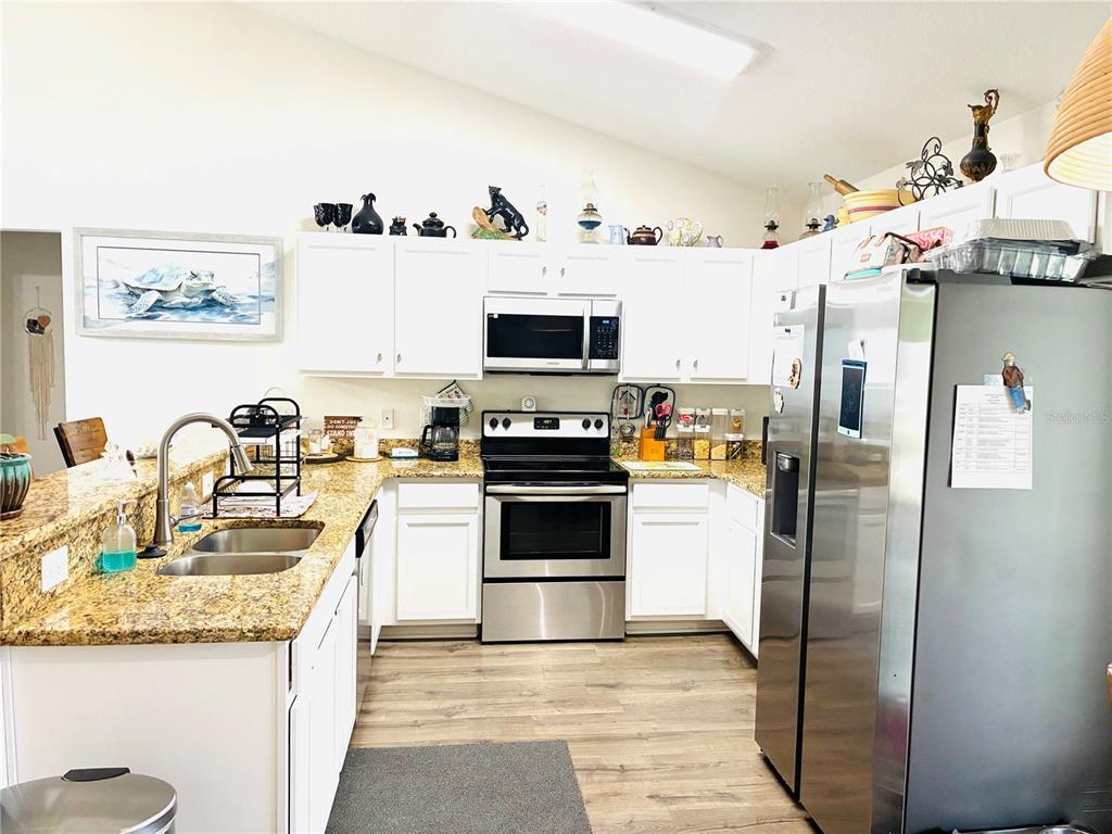 A kitchen features white cabinets, stainless steel appliances, and granite countertops with a double sink — 40551 E 5TH AVENUE, UMATILLA, FL