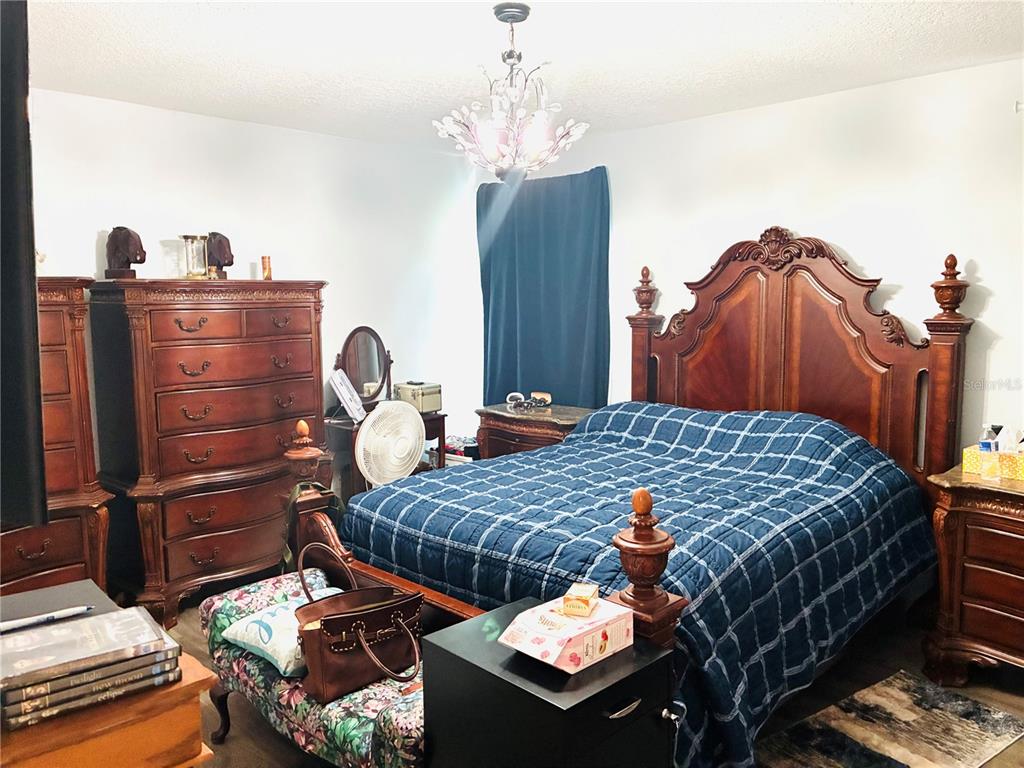 A bedroom features a large wooden bed frame, a tall dresser, and a floral bench — 40551 E 5TH AVENUE, UMATILLA, FL