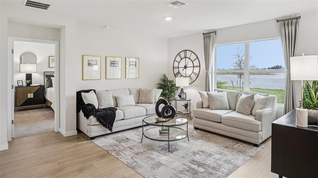 A living room with two beige sofas, a glass coffee table, and a lake view — 9698 SAND DUNE LANE, PUNTA GORDA, FL