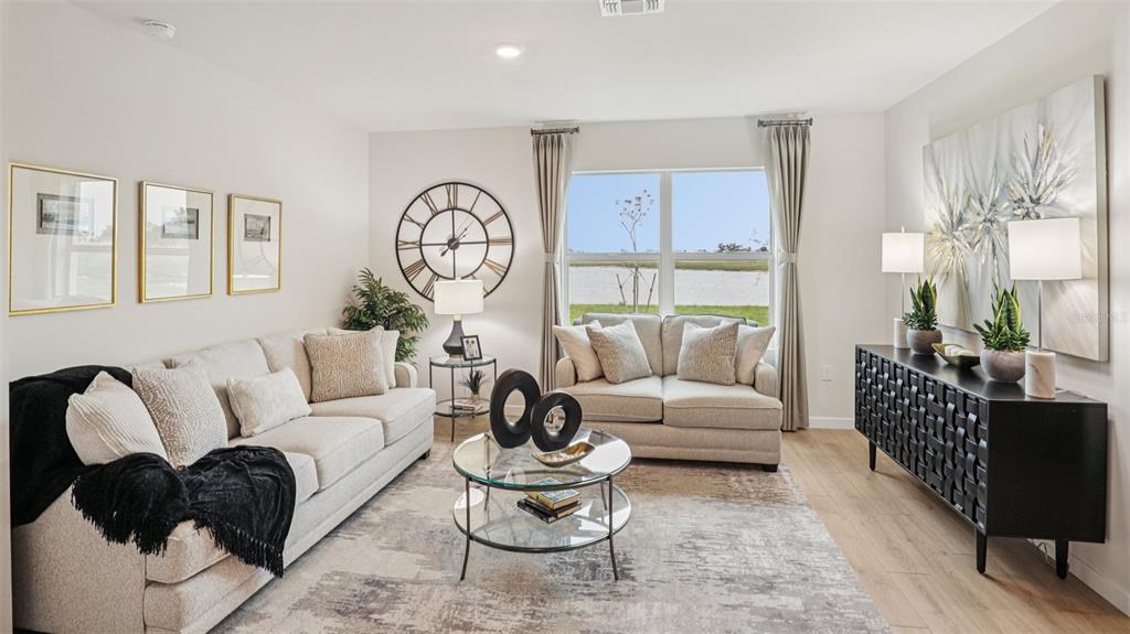 A living room features a beige sofa, a loveseat, a glass coffee table, and large windows — 9698 SAND DUNE LANE, PUNTA GORDA, FL