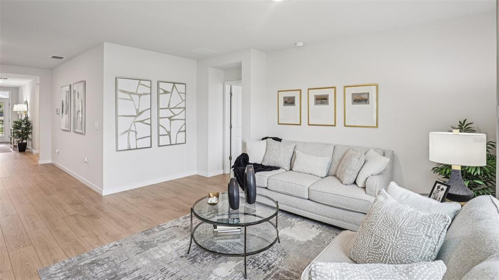 A living room features light wood flooring, a gray sofa, and a glass coffee table — 9698 SAND DUNE LANE, PUNTA GORDA, FL