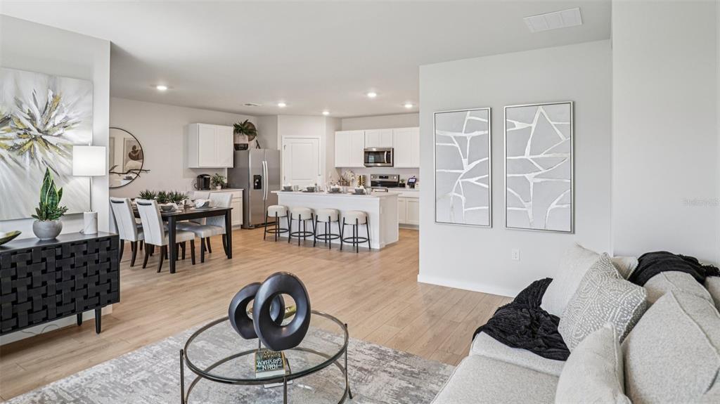 This open-concept living area features a kitchen with a white island and dining space — 9698 SAND DUNE LANE, PUNTA GORDA, FL