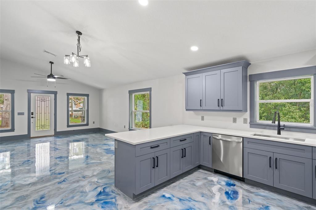 An open-concept kitchen and living area features blue-swirled epoxy flooring and gray cabinetry — 478 LINCOLN AVENUE, BROOKSVILLE, FL
