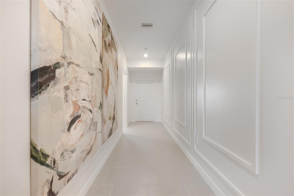 A hallway with light tile flooring, white paneled walls, and large abstract art on display — 3508 IMARI STREET, NORTH PORT, FL