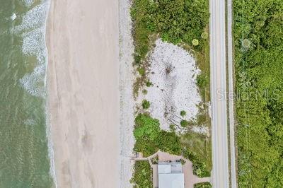 An aerial view shows a sandy beach, a coastal lot with vegetation, and a nearby road — 6965 HIGHWAY A1A, MELBOURNE BEACH, FL