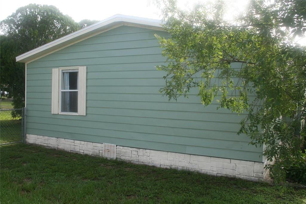 The exterior side of a light green house features horizontal siding and a stone foundation — 10035 SE 126TH LANE, BELLEVIEW, FL