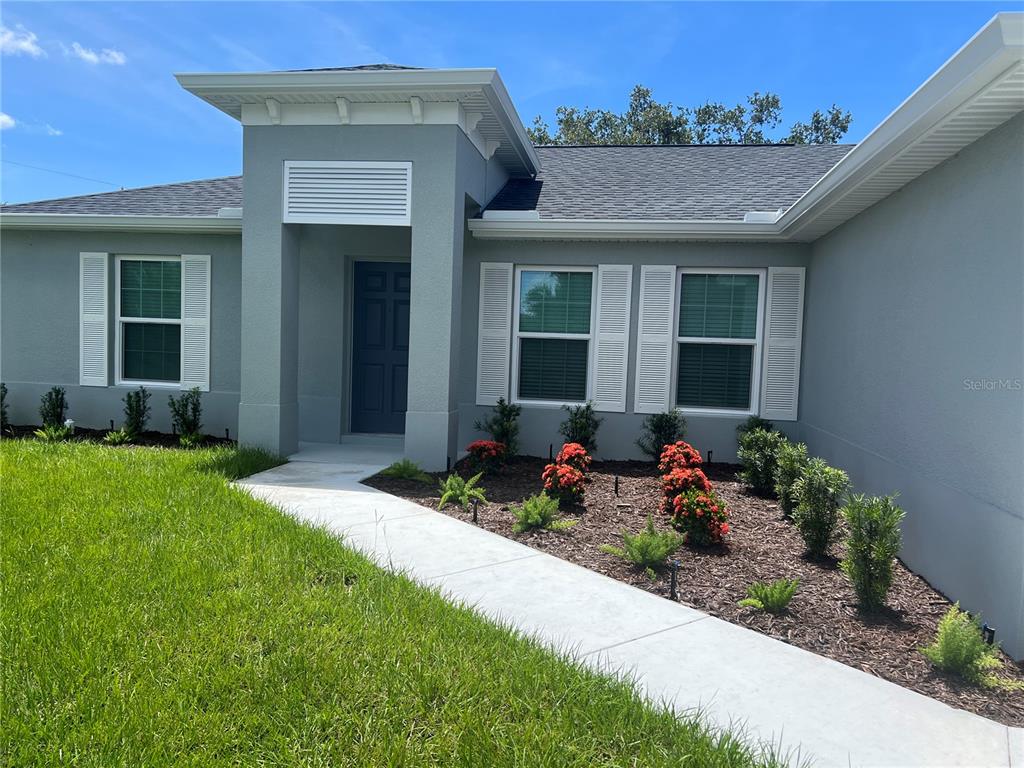 A single-story house exterior features a gray facade, white shutters, and a concrete walkway — 4895 LAS ALMANOS AVENUE, NORTH PORT, FL