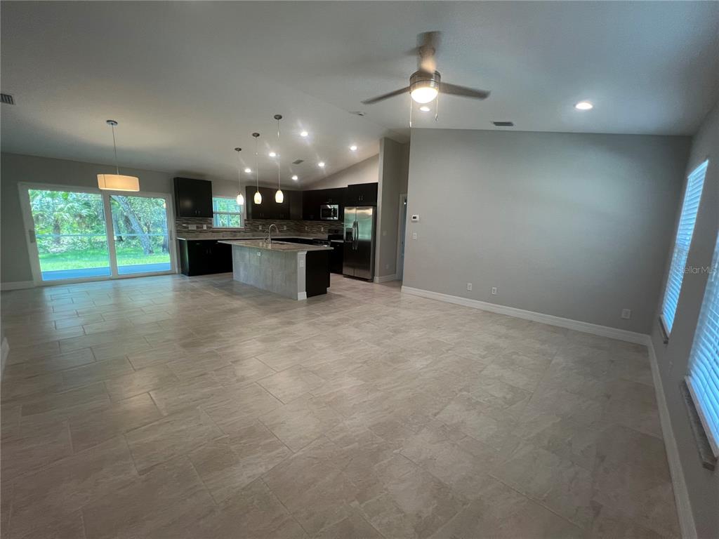 An open-concept kitchen and living area features tile flooring, dark cabinets, and a center island — 4895 LAS ALMANOS AVENUE, NORTH PORT, FL