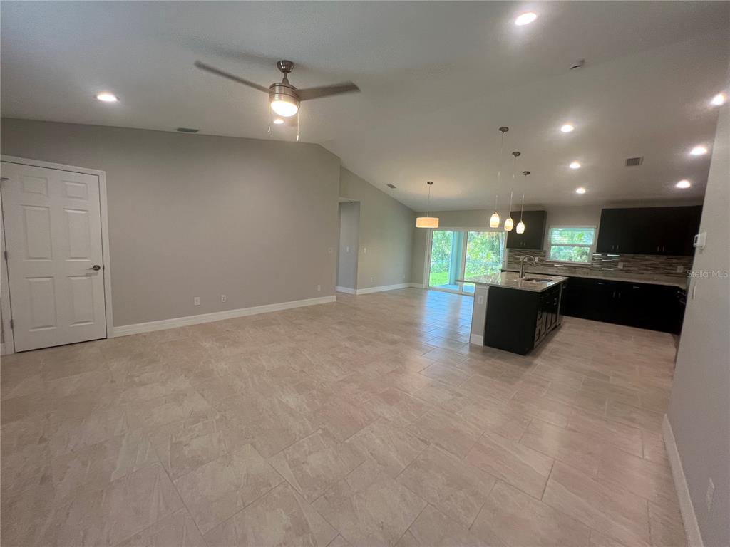 An open-concept living area features light tile flooring, a vaulted ceiling, and a modern kitchen — 4895 LAS ALMANOS AVENUE, NORTH PORT, FL