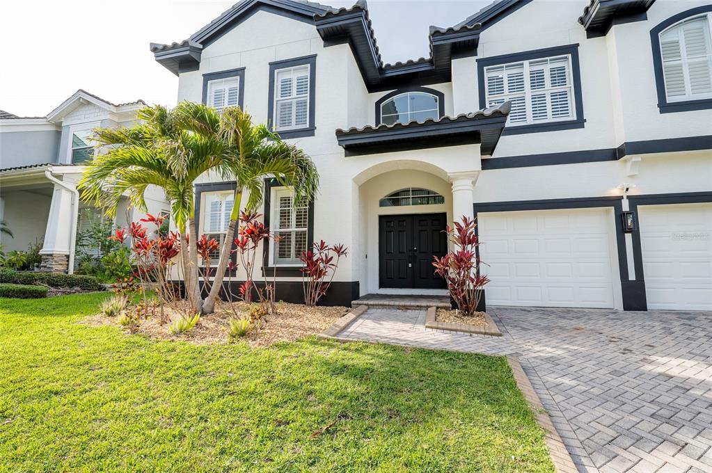 A two-story house with white stucco walls, black trim, a paved driveway, and palm trees — 2348 MESSENGER CIRCLE, SAFETY HARBOR, FL