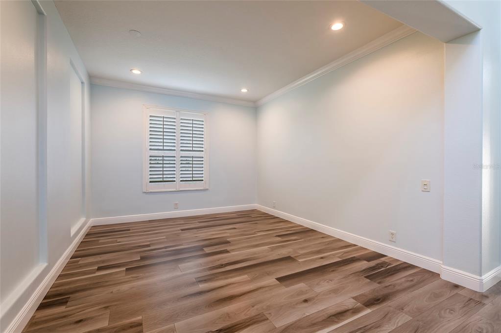 An empty room with light blue walls, crown molding, and wood-look flooring — 2348 MESSENGER CIRCLE, SAFETY HARBOR, FL