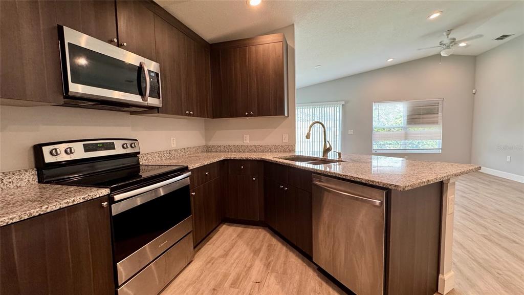 A kitchen features dark wood cabinets, granite countertops, and stainless steel appliances — 5 N HART BOULEVARD, ORLANDO, FL