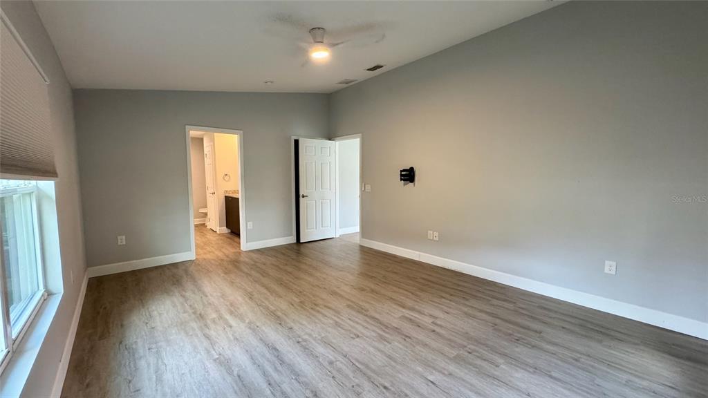 A bedroom with light wood-look flooring, gray walls, a ceiling fan, and two doorways — 5 N HART BOULEVARD, ORLANDO, FL