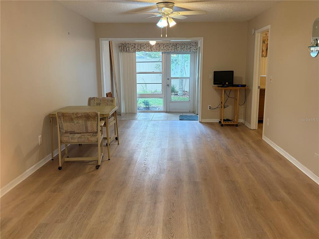 A dining area with light wood-look flooring, a ceiling fan, and a glass door — 2465 NORTHSIDE DRIVE UNIT 1502, CLEARWATER, FL