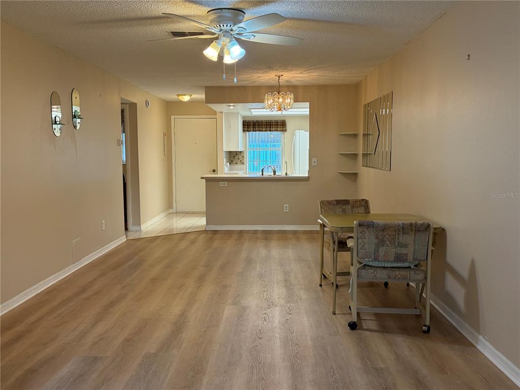 A dining area with wood-look flooring, a ceiling fan, and an open kitchen pass-through — 2465 NORTHSIDE DRIVE UNIT 1502, CLEARWATER, FL