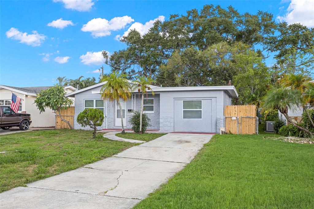 A single-story gray house with a concrete driveway, a front lawn, and palm trees — 2443 26TH AVENUE S, ST PETERSBURG, FL